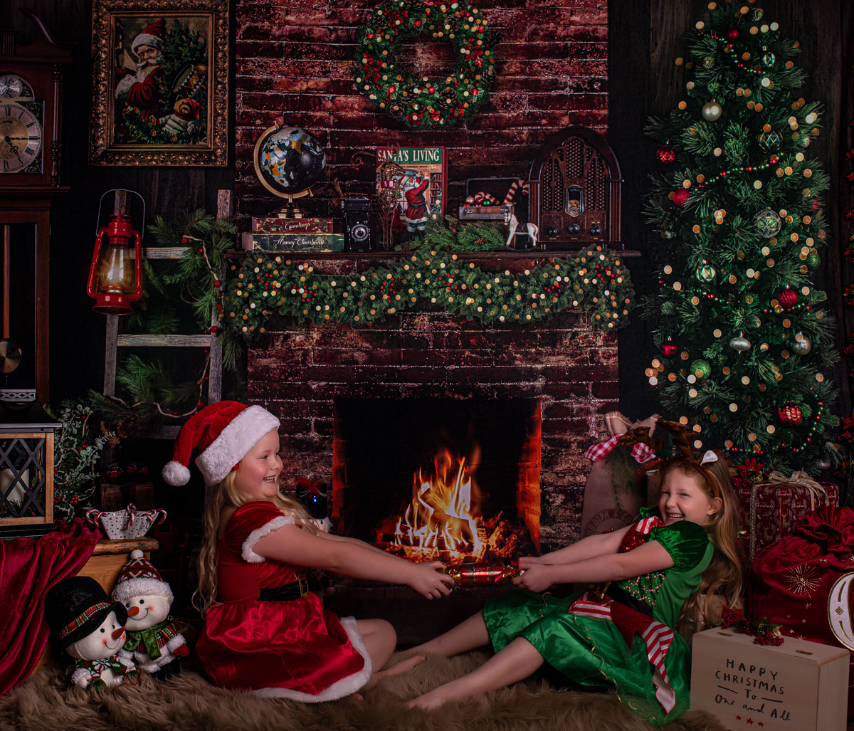 Two sisters sharing a Christmas moment beside the fireplace at Laycock Photography