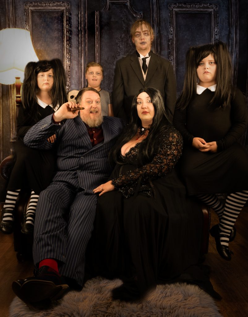 Family dressed as the Addams Family in a Halloween portrait at Laycock Photography's Stalybridge studio, serving Stockport and Cheshire.