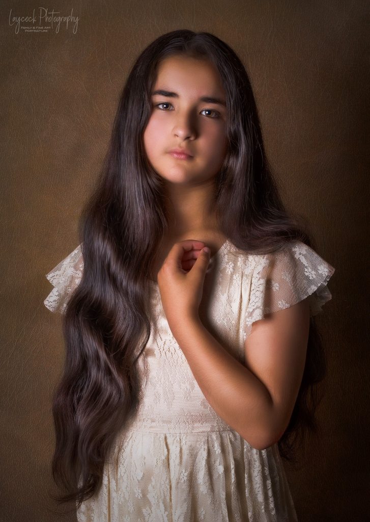 Young asian girl with long dark hair over her shoulder. Her left had across her chest.
