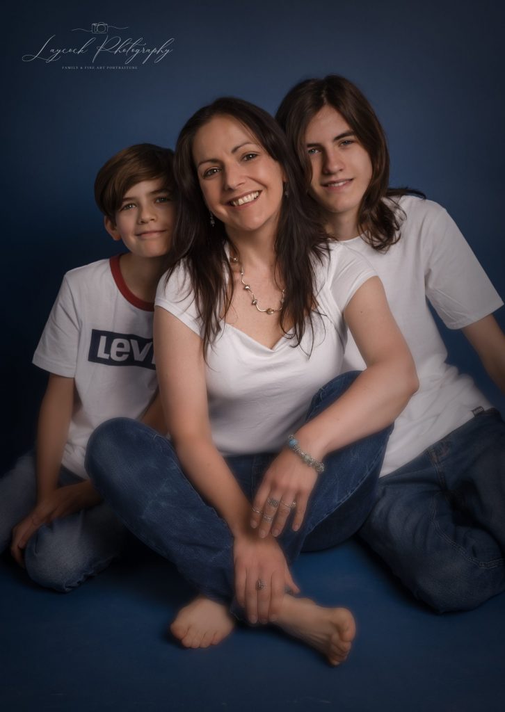 Mother and two sons sat on the floor on a blue background